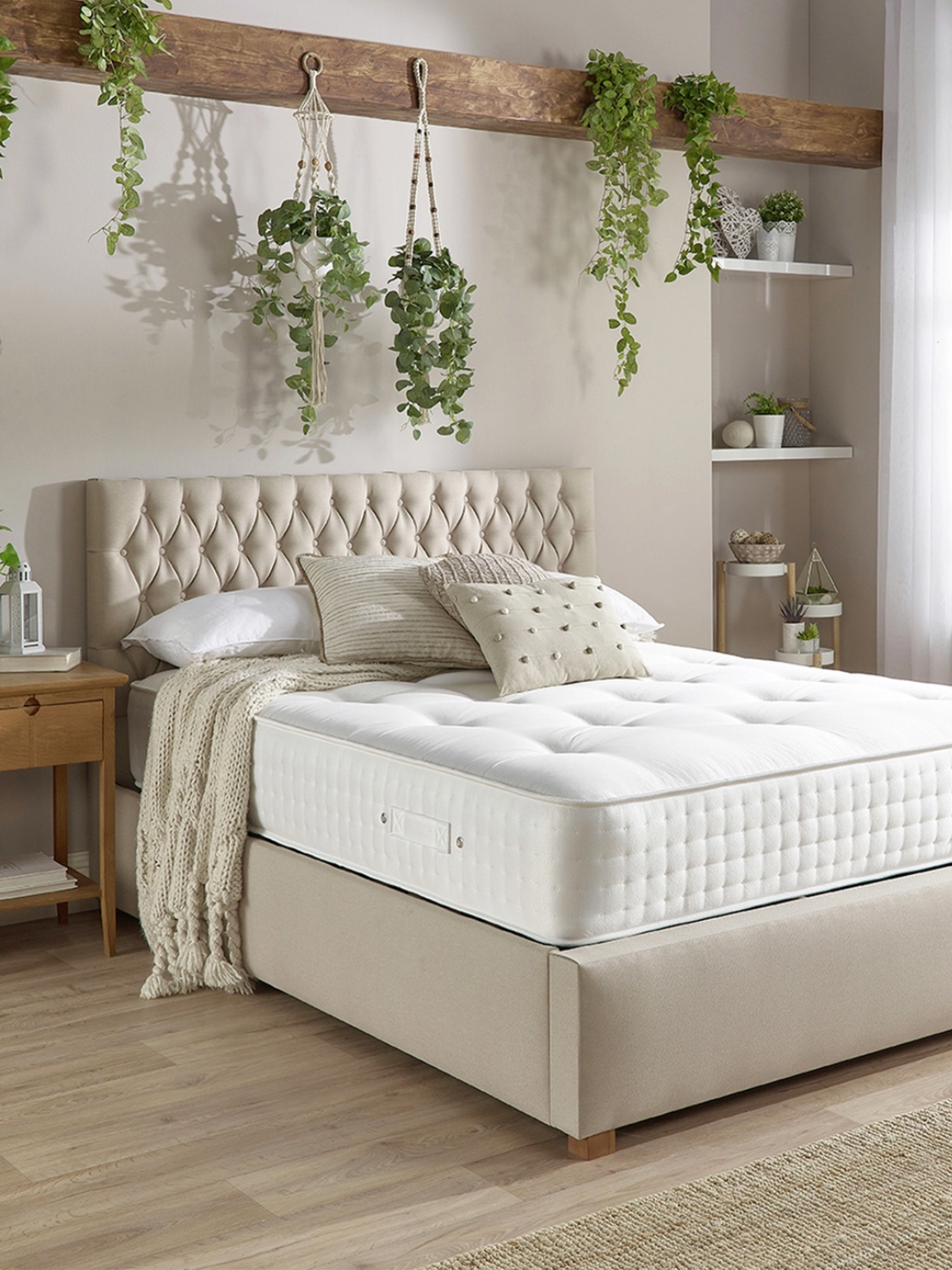 An organic mattress in a bedroom below hanging plants