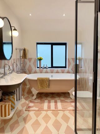 Pink geometric tiled bathroom with black accents and painted tub