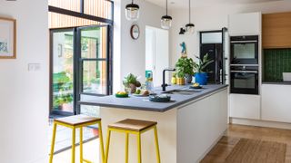 white kitchen diner with yellow bar stools and Crittall style doors