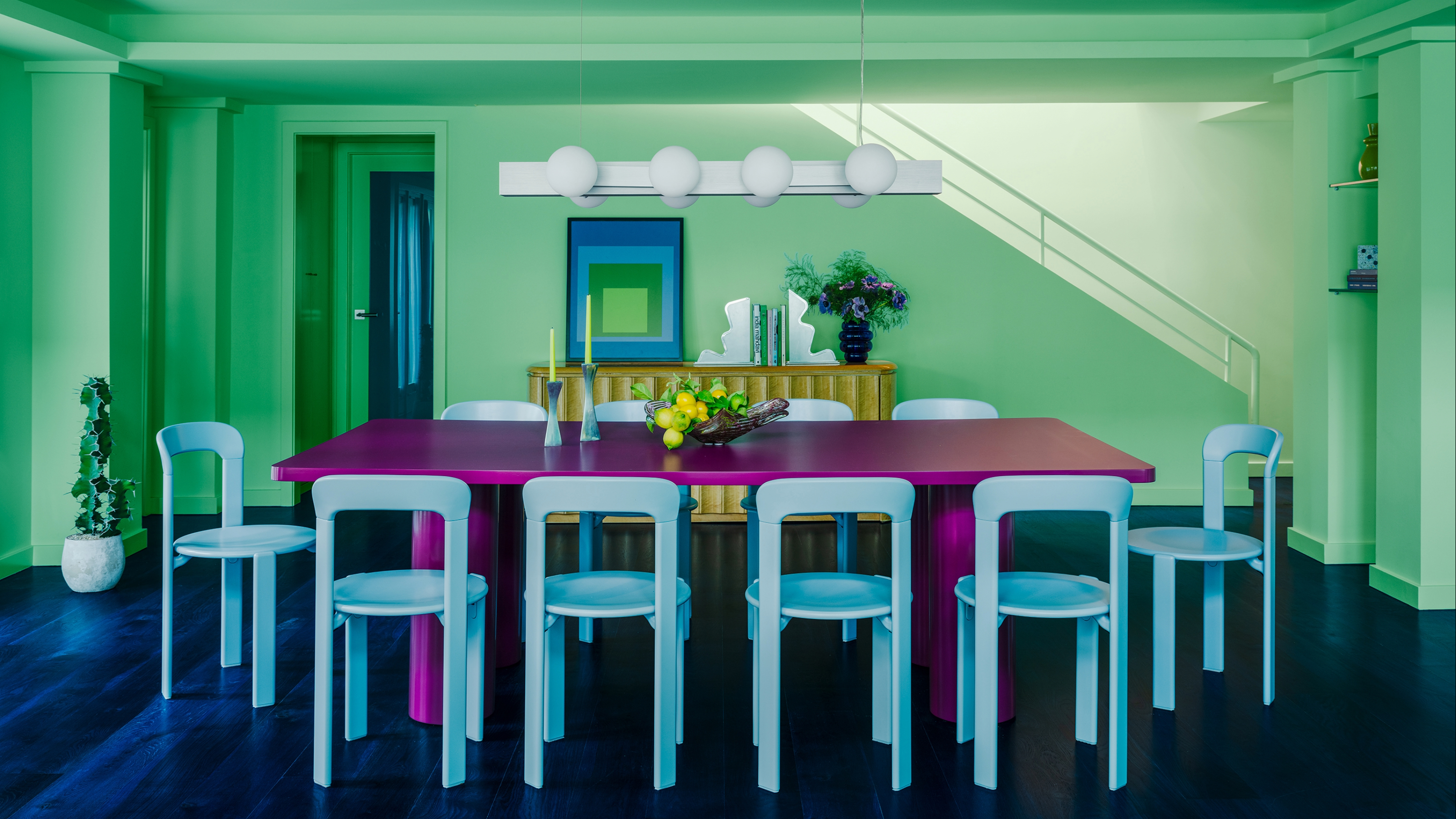 A contemporary dining room in pastel green and blue with a bright purple dining table