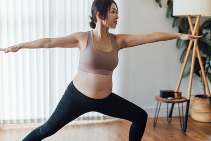 Benefits of yoga: Pregnant woman practices Warrior 2 at yoga studio