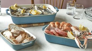 STAUB Ceramique set on a white table with a lobster, oysters, and a basket of bread in them