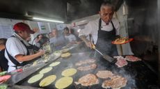 Jacinto Rodriguez grills the meat while Carolina Gonzalez prepares tortillas at El Califa de Leon 