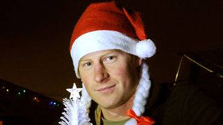 Prince Harry is cleanly shaven and wears a Christmas hat