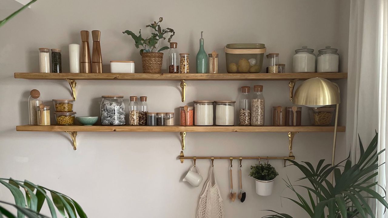 wooden shelving unit with food containers and hanging rails by a table in a dining room