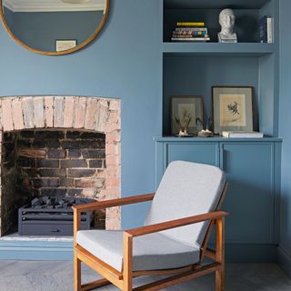 Blue living room with brick fireplace and grey armchair