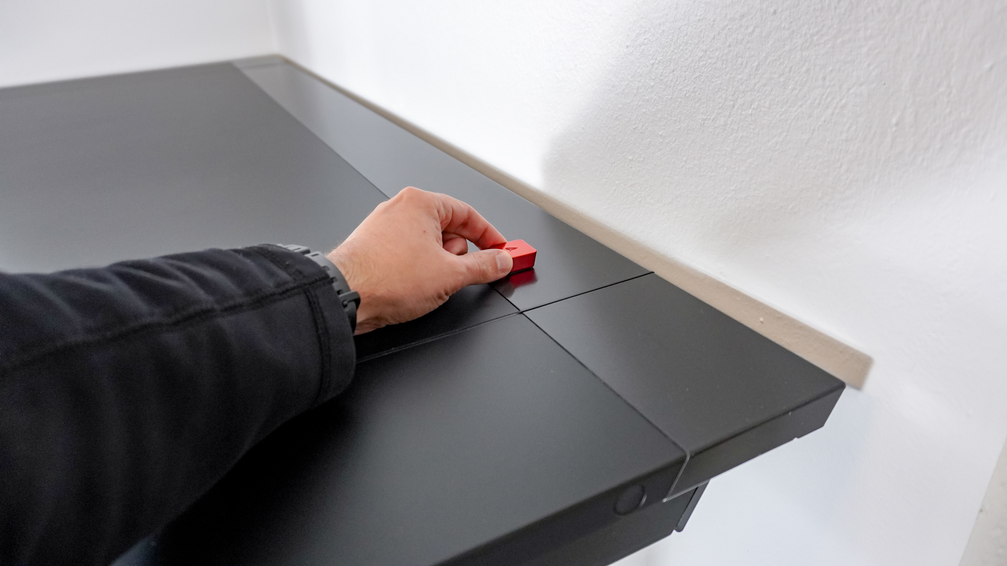 A person attaching a magnetic cable anchor to the metal back of the Secretlab Magnus Evo