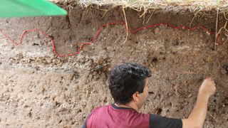 Archaeologist draws lines in an excavation site to mark sediment layers from different time period.