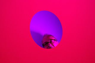 Man peeking through purple hole