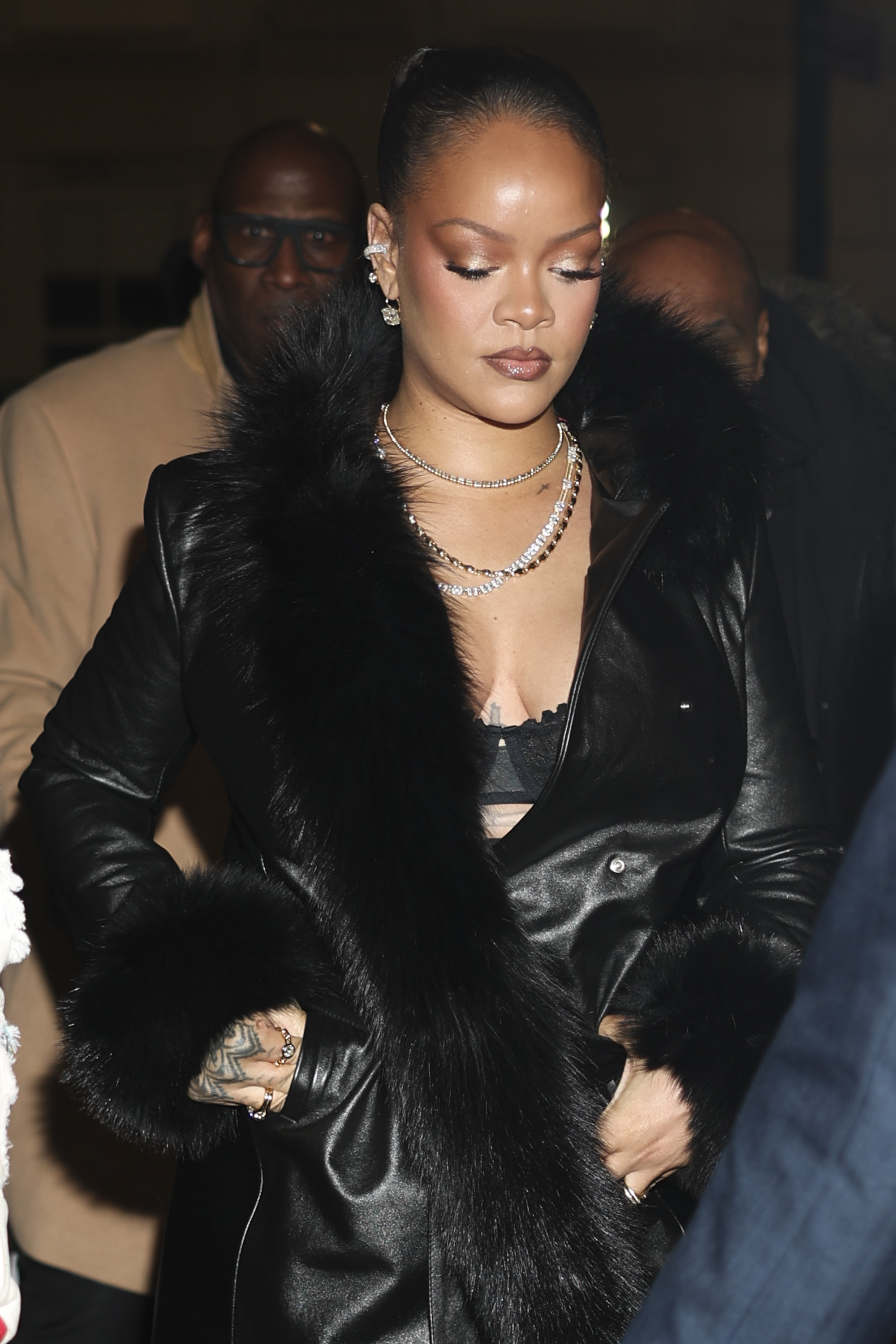 Rihanna is seen on February 13, 2026 in New York City wearing a fur-trimmed leather trench coat, lace underwear, sheer tights, and pointed-toe pumps
