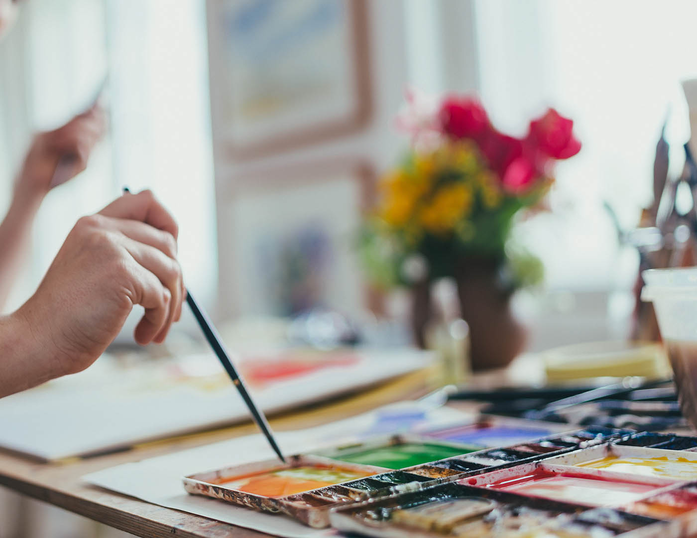 Woman painting watercolour with a fine brush, close-up.