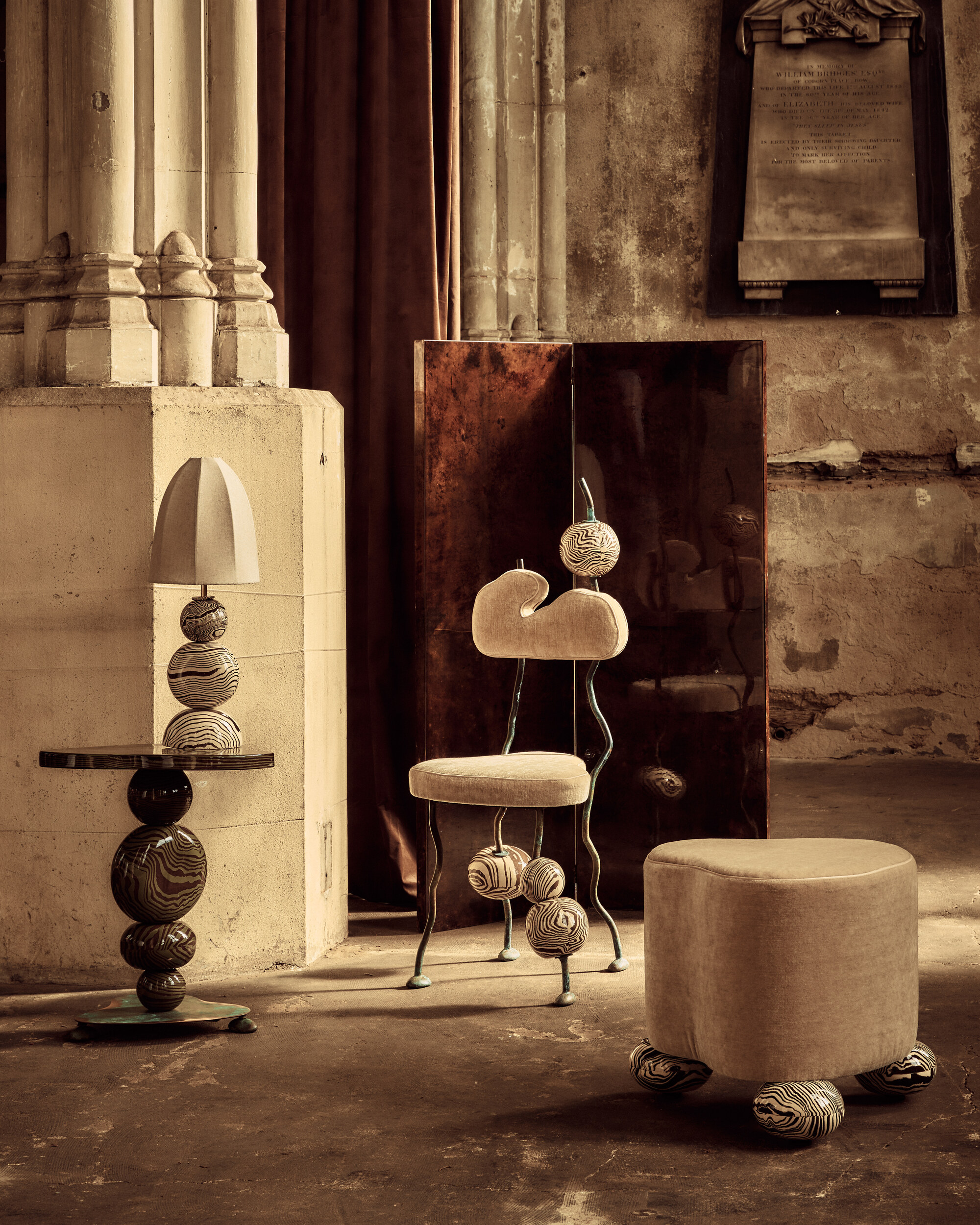 image of a matching sculptural chair, footstool, side table, and lamp in a warehouse-style room