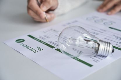 A woman at home reading a utility bill