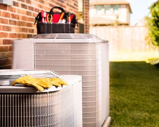 HVAC heating systems being serviced outside red brick home