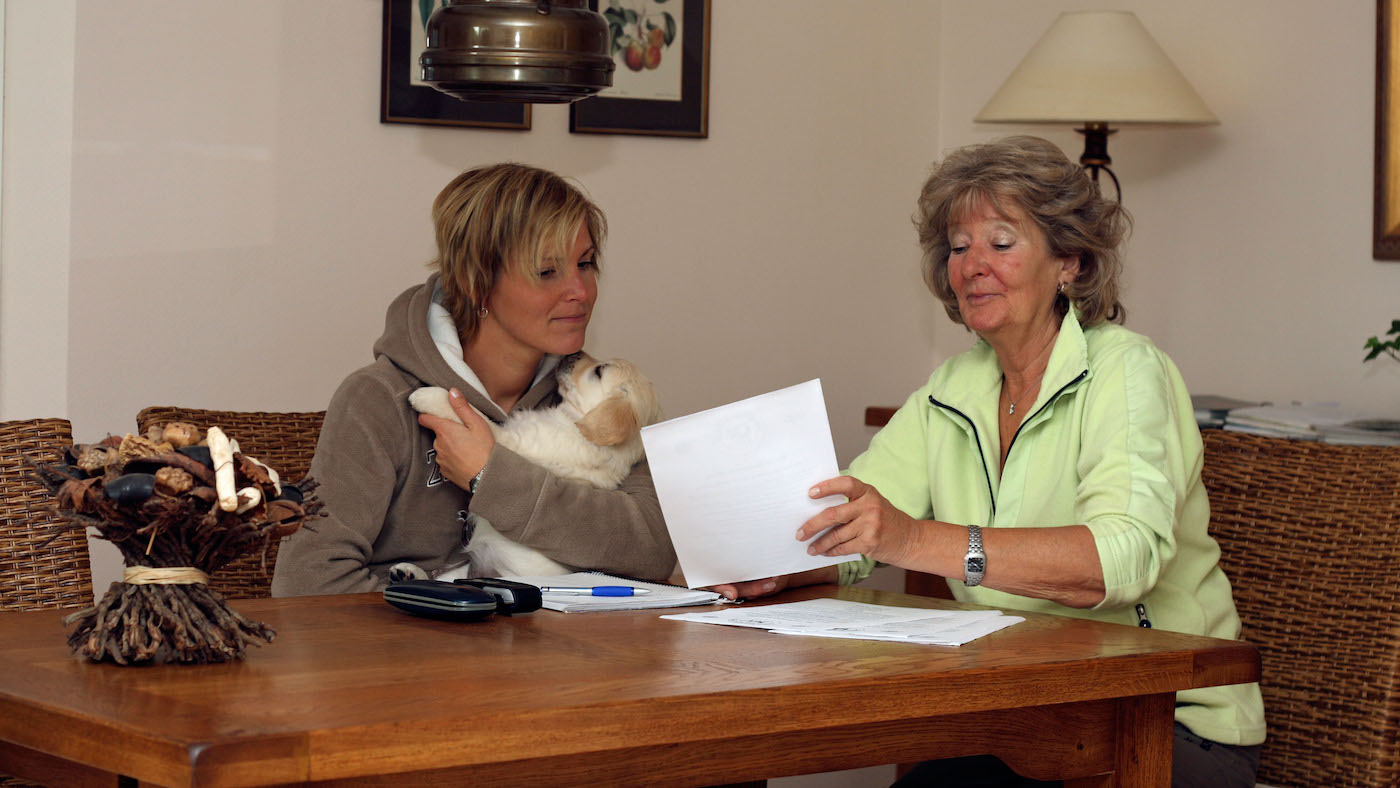 Puppy owner and breeder discussing paperwork about buying a new puppy