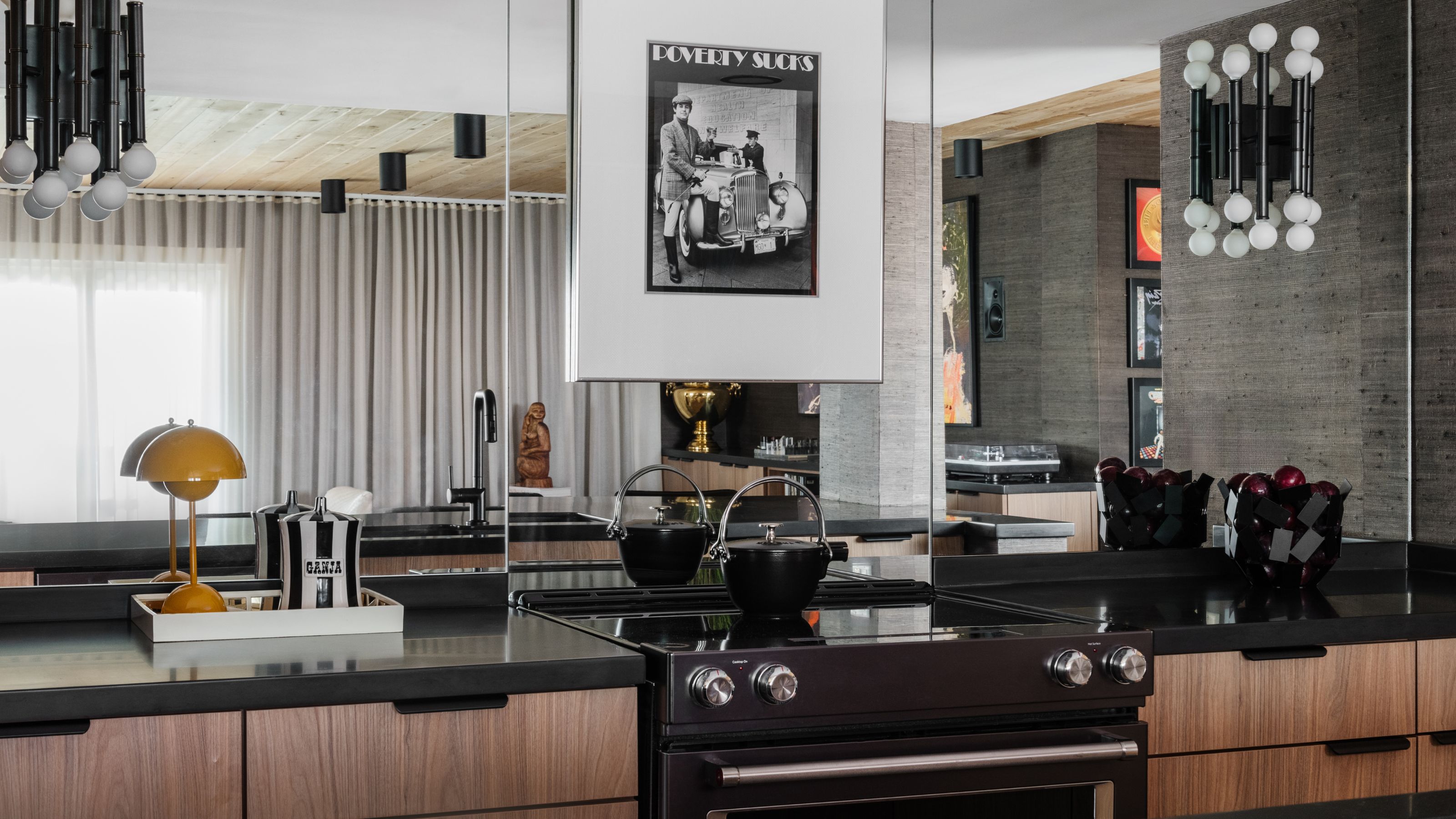 Contemporary kitchen featuring a mirrored backsplash, black countertops, and black-and-white artwork