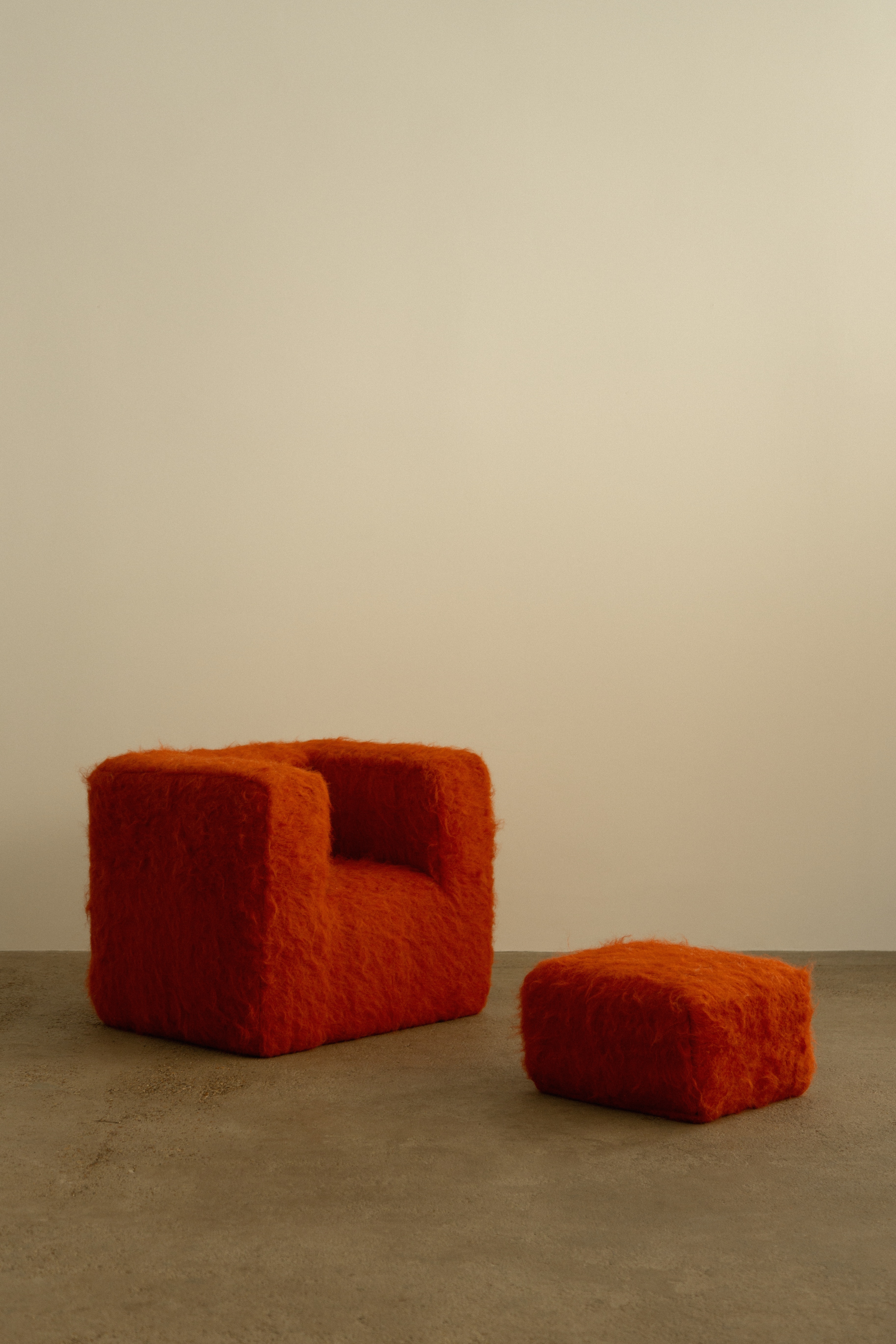 A series of textile creations with an abstract, textural wool feel sit in an industrial showroom alongside iconic modernist designs.