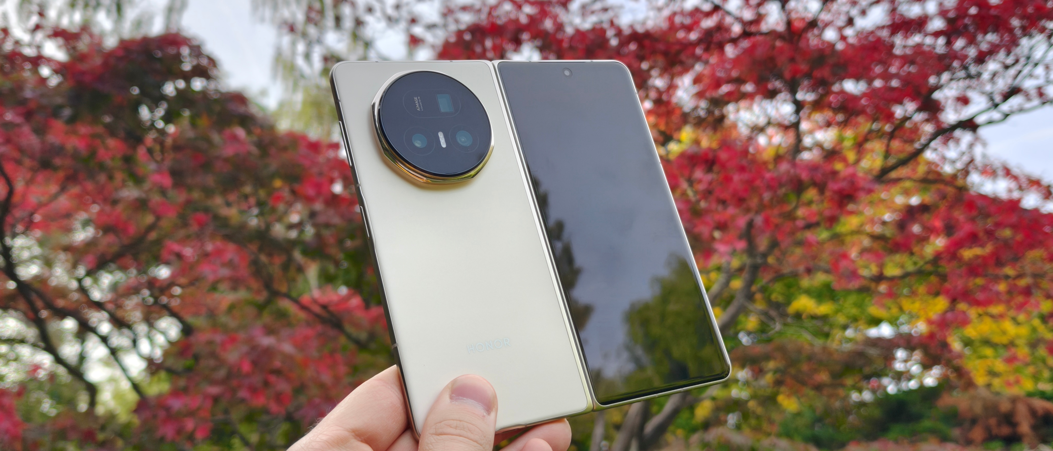 The Honor Magic V5 unfolded against a red tree