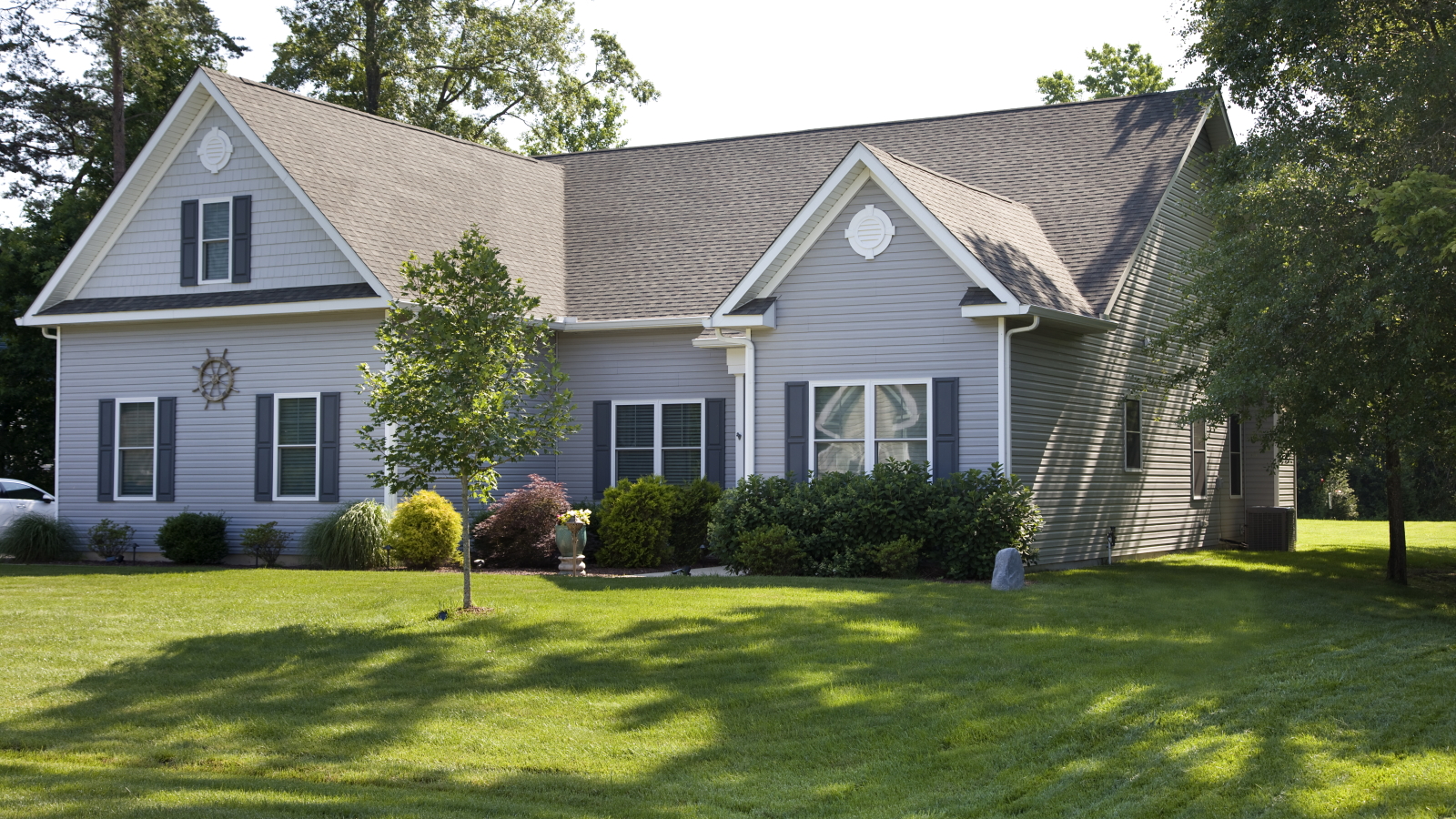 A suburban home with a lush, green front lawn in the summer