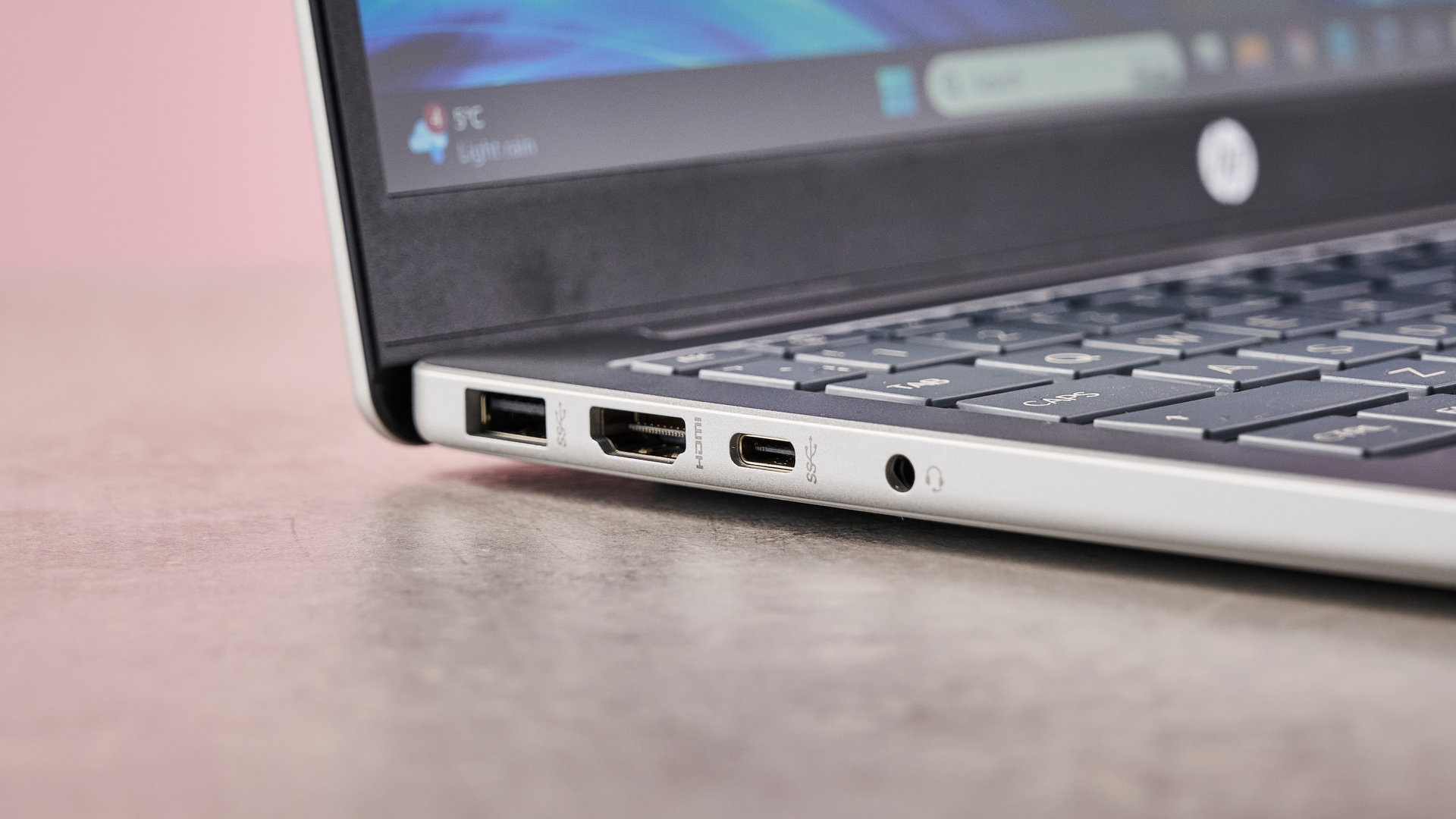Close-up of ports on left-hand side of HP Laptop 14, on desk with pink wall in background