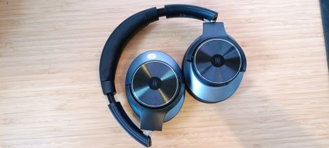 A pair of black and grey OneOdio A10 headphones sitting on a wooden desk