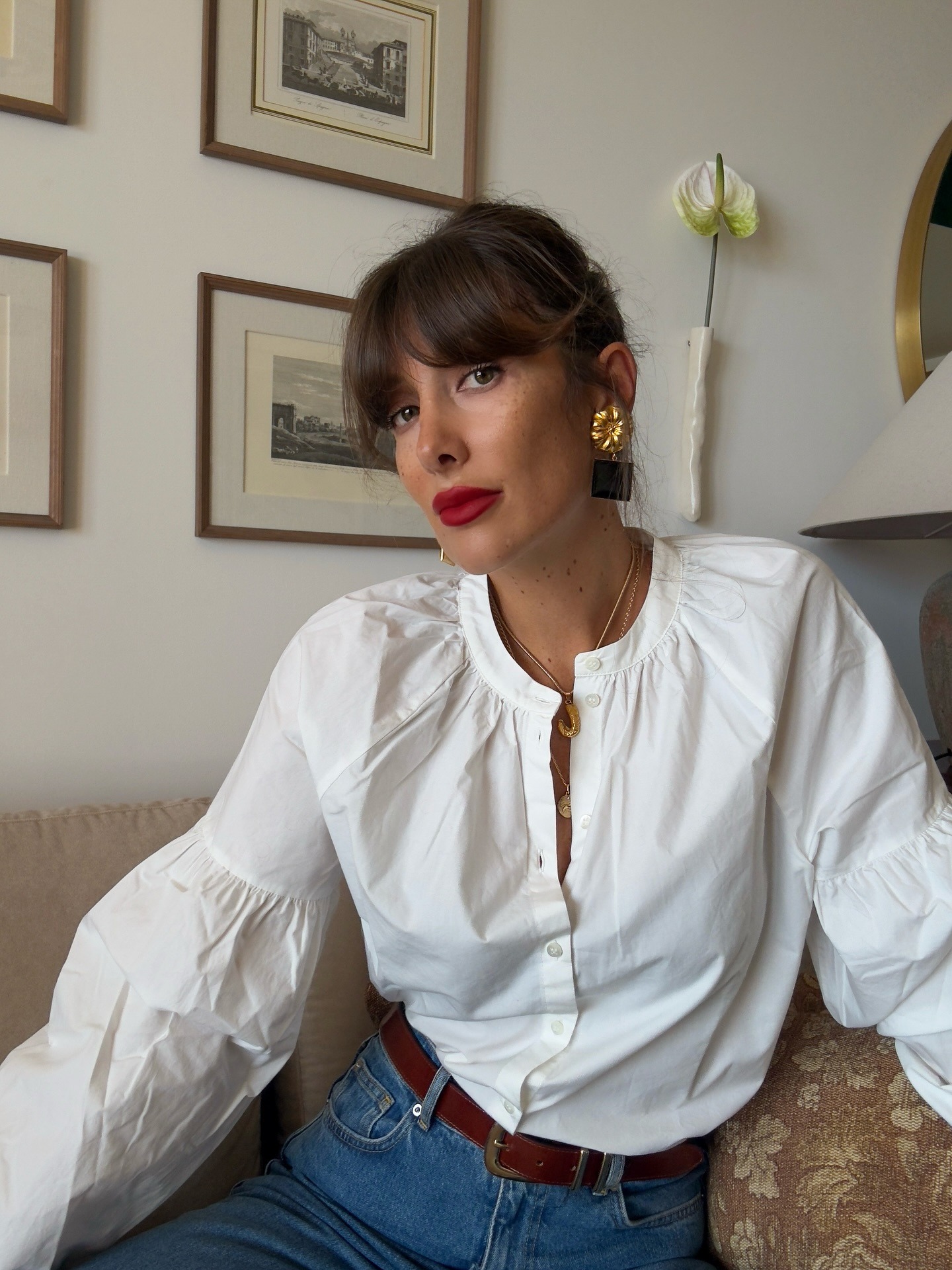 A woman wearing a white blouse with a tousled updo hairstyle and a fringe