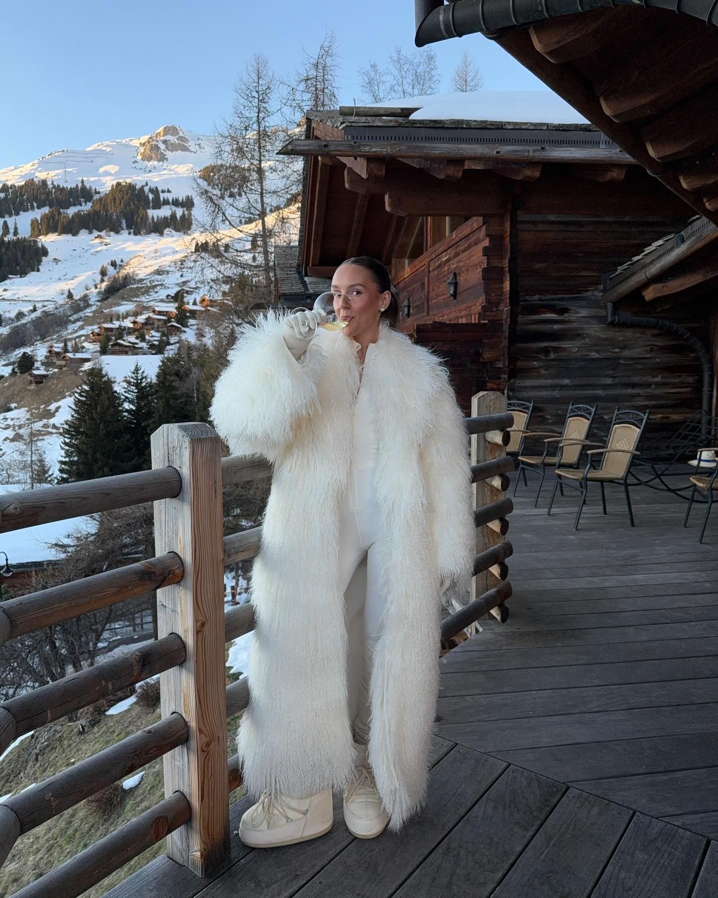 Emma wears a white long fur coat, white thermals, and white moon boots.