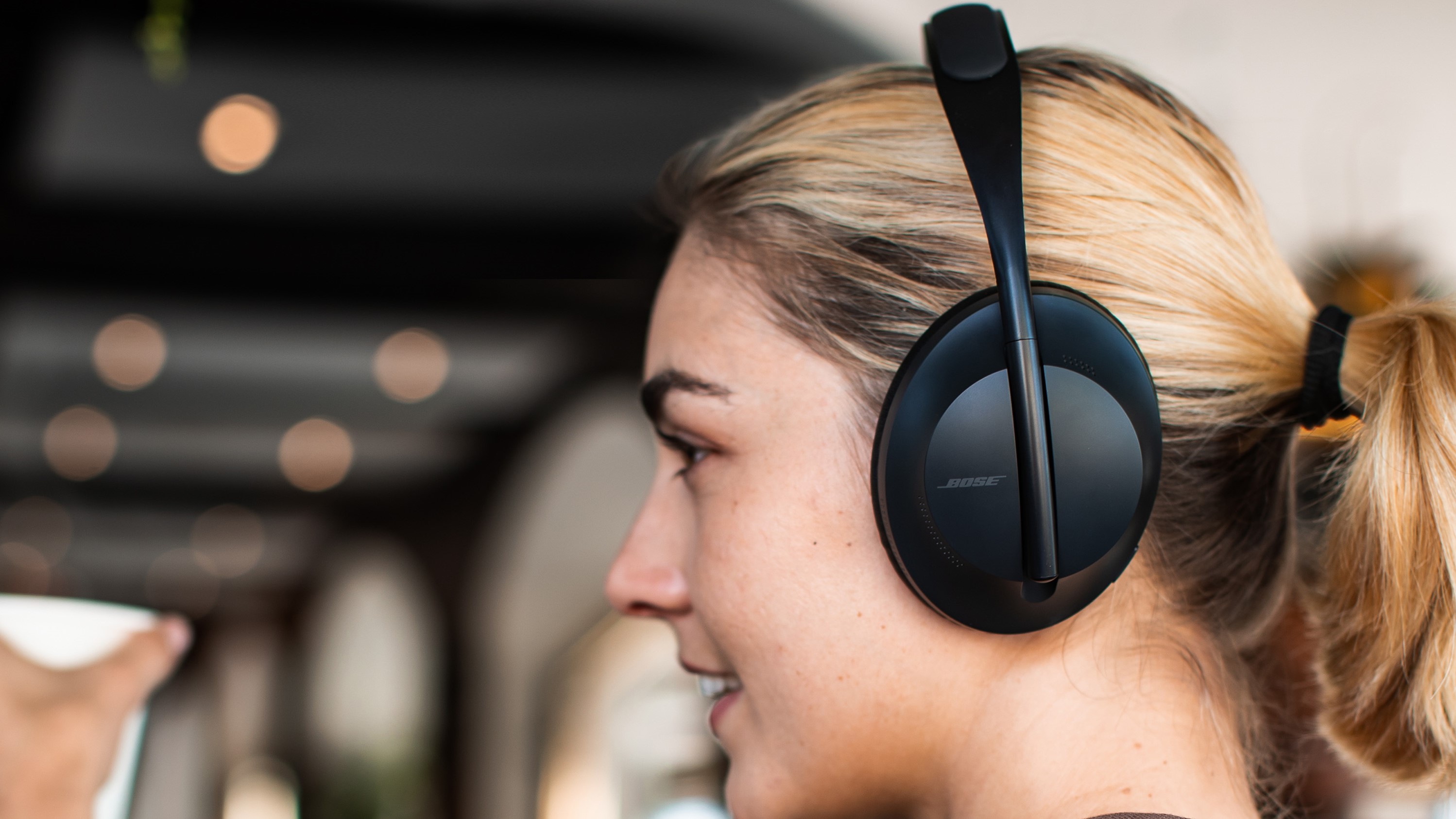 Seorang wanita mengenakan Bose Noise Cancelling Headphones 700 berwarna hitam