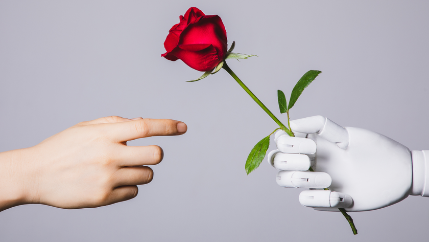 A stock photo of a human hand reaching for red rose held in a robotic hand.