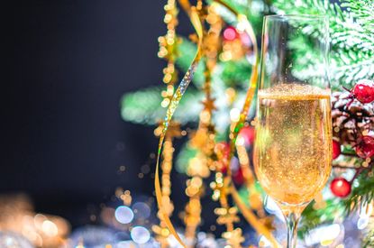 A glass of sparkling wine in front of a Christmas tree