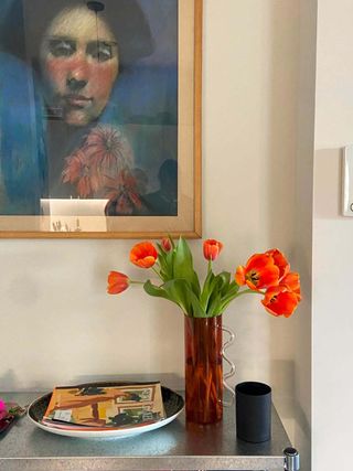 A vase of tulips photographed on a table against a white wall with picture frame in the home of Christopher John Rogers