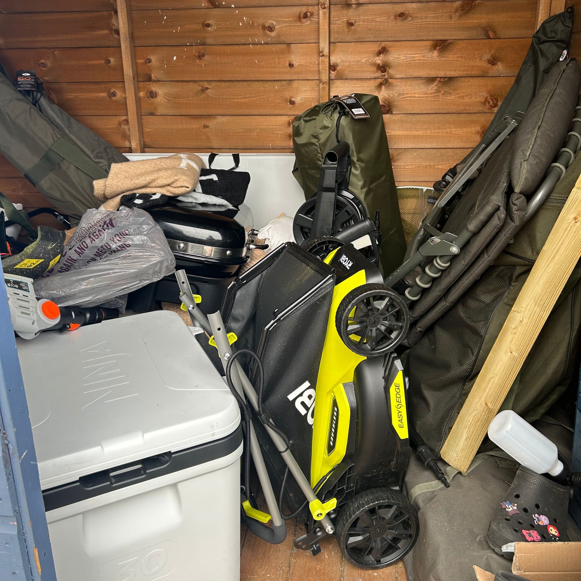 Ryobi lawnmower folded in busy shed