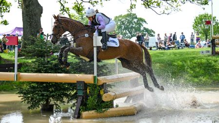 Gemma Stevens and Chilli Knight jump a cross-country fence in water at Badminton 2026.