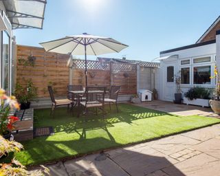 Private backyard area with artificial grass in the sunshine