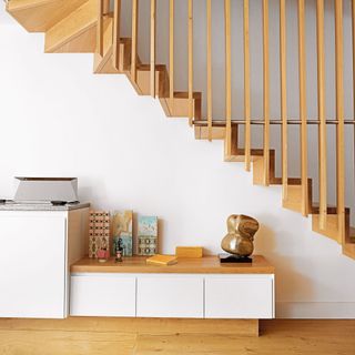 White living room with wooden stairs and storage units