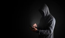 Hooded scammer calling on a cellphone