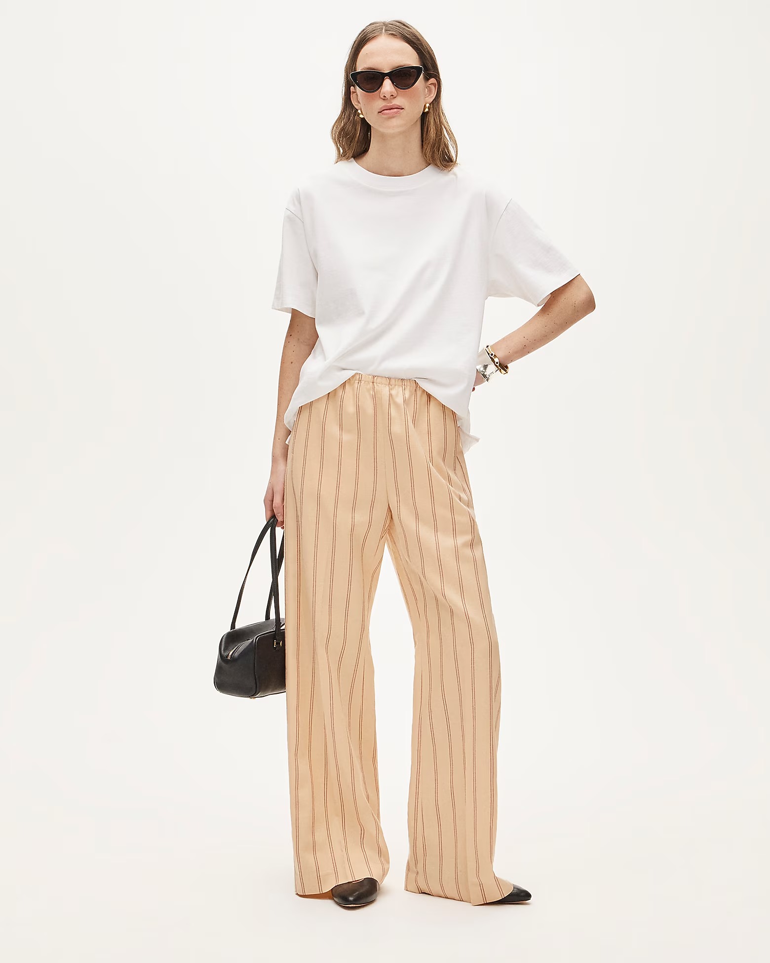 J.Crew outfit with black cat-eye sunglasses, a white T-shirt, black shoulder bag, relaxed striped pants, and black ballet flats