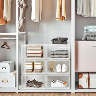 Clear plastic storage boxes stacked at the bottom of a wardrobe space to keep shoes and clothing