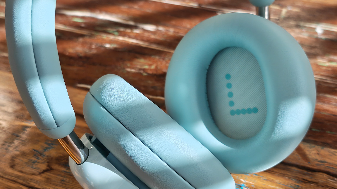 CMF Headphone Pro; a pair of light green headphones on a wooden table