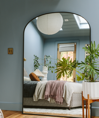 A mirror view of a blue bedroom, with a potted plant.