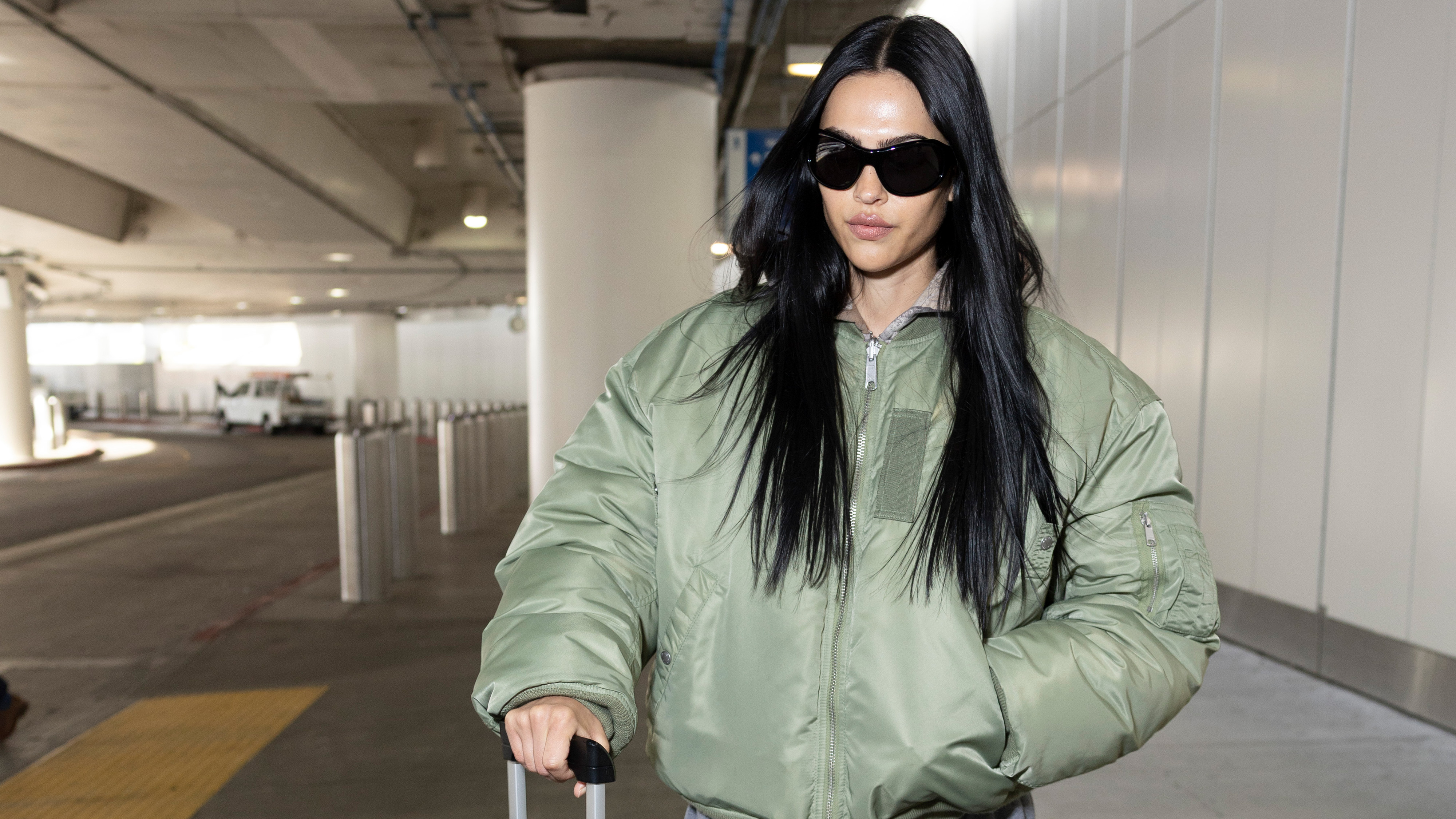 Amelia gray wears sunglasses and a green puffer jacket.