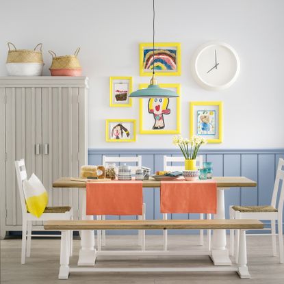 Dining room with wall panelling, coloured picture frames and seating bench