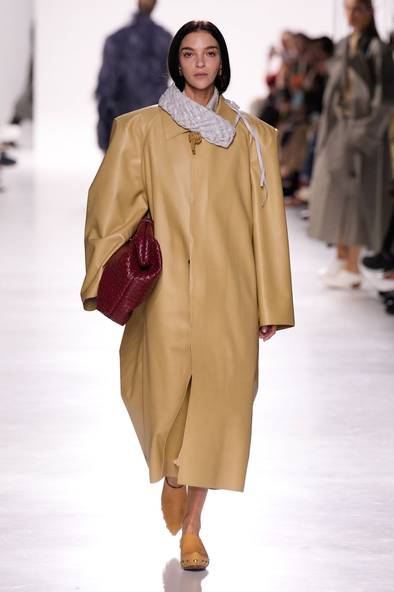 Bottega Veneta model walking in the S/S 26 show wearing an oversize leather coat and carrying a new version of the Lauren bag.