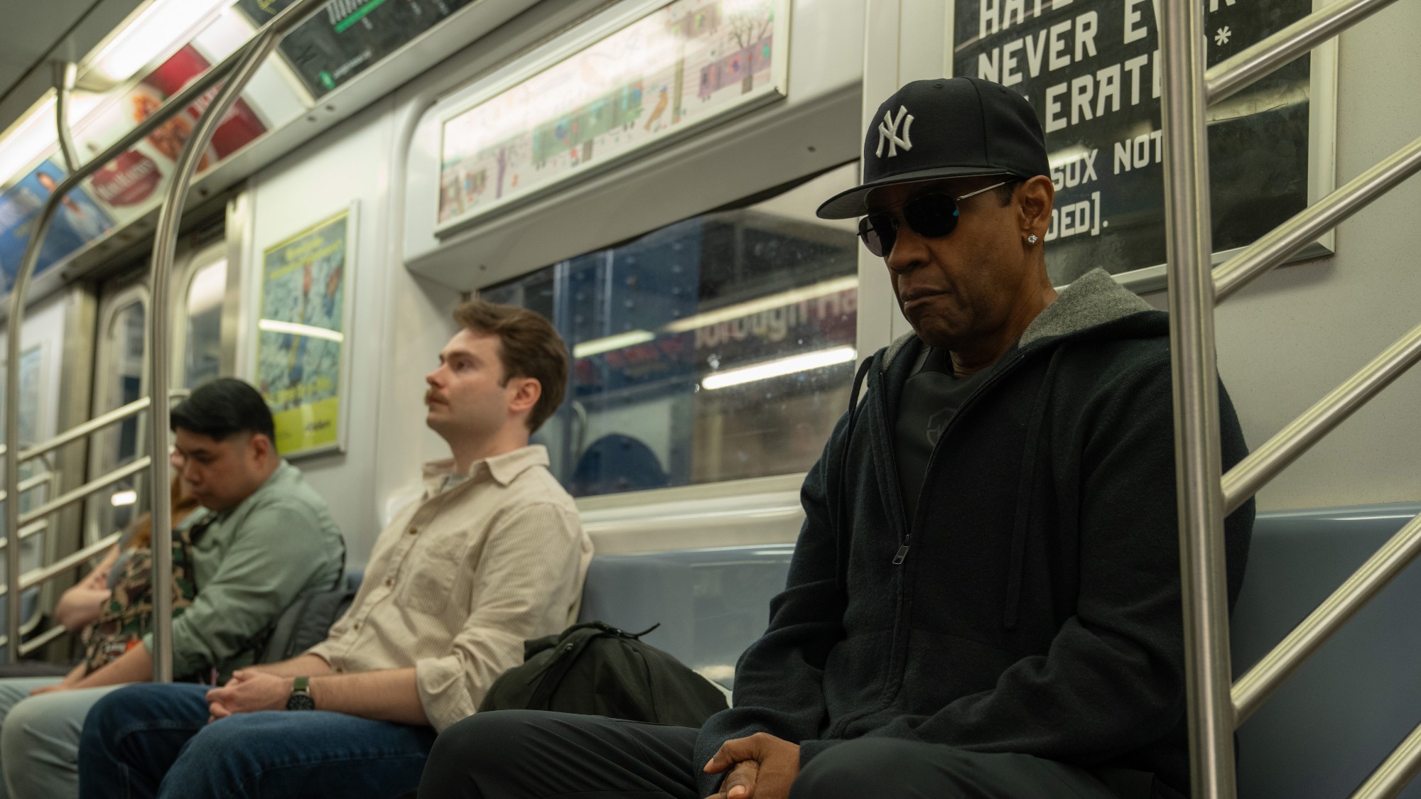 Denzel Washington sitting on the subway in a New York Yankees hat in Highest 2 Lowest