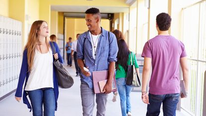 High school students walking along hallway chatting