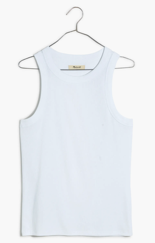 a white ribbed tank top worn by Gigi Hadid in front of a plain backdrop