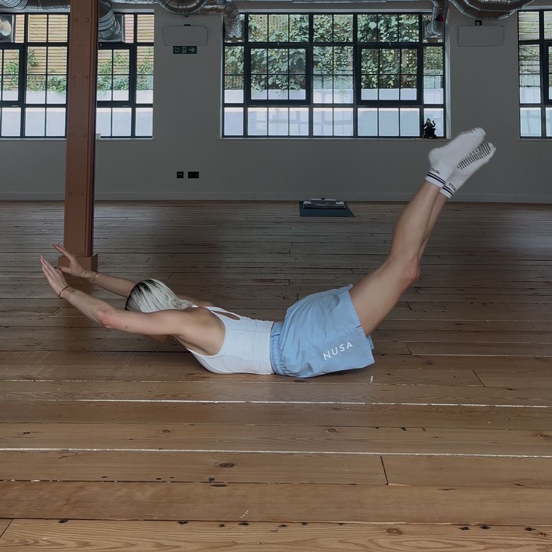 A woman practicing the Pilates Swan Dive in a Yoga Studio