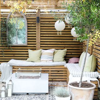 Wooden outdoor seating area with cushions and pendant lights