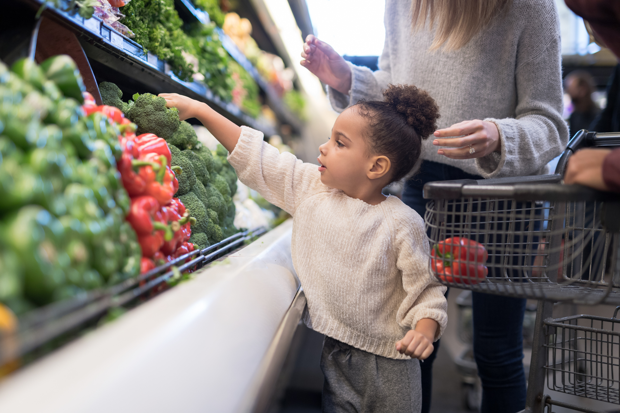 Child picks vegetables up in supermarket