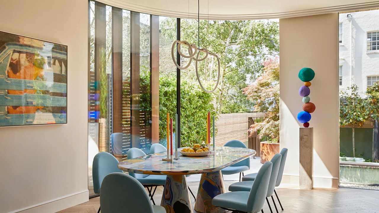 a dining room with a curved patio door, colorful artwork and furniture, and a view out to the garden